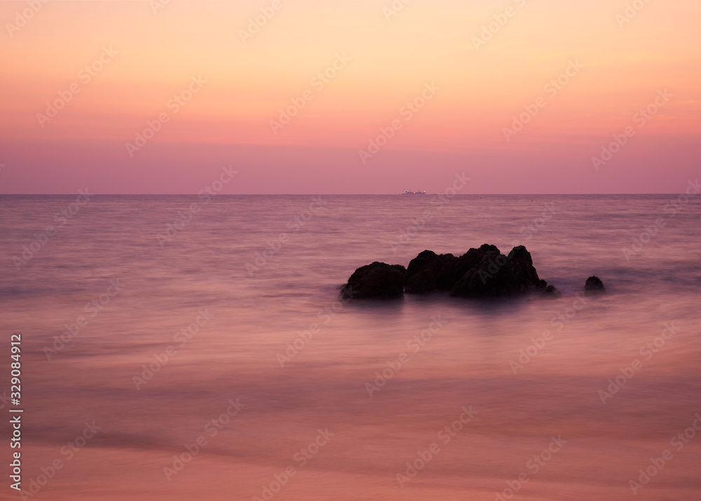 Long exposure scene of beautiful sunset sky and rocks in the sea