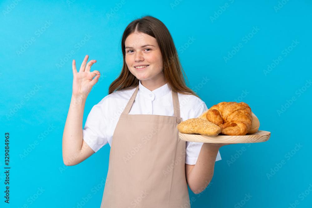 Ukrainian teenager chef uniform. Female baker holding a table with several breads showing ok sign with fingers Ukrainian teenager chef uniform. Female baker holding a table with several breads showing ok sign with fingers