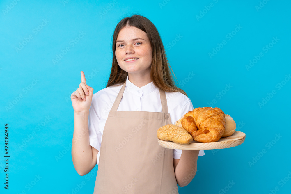 Ukrainian teenager chef uniform. Female baker holding a table with several breads intending to realizes the solution while lifting a finger up