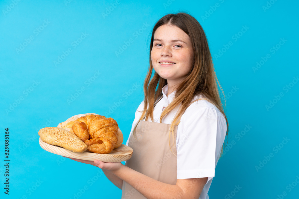 Ukrainian teenager chef uniform. Female baker holding a table with several breads smiling a lot Ukrainian teenager chef uniform. Female baker holding a table with several breads smiling a lot