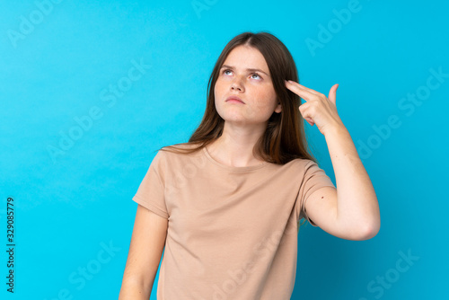 Ukrainian teenager girl over isolated blue background with problems making suicide gesture © luismolinero