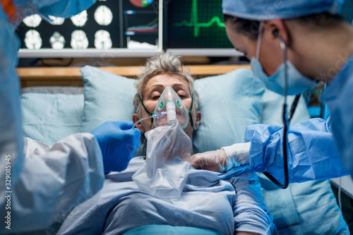 Doctors examining coronavirus infected patient lying on bed in hospital