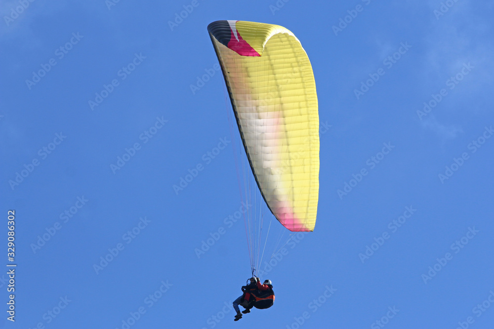 Tandem Paraglider flying wing in a blue sky Tandem Paraglider flying wing in a blue sky