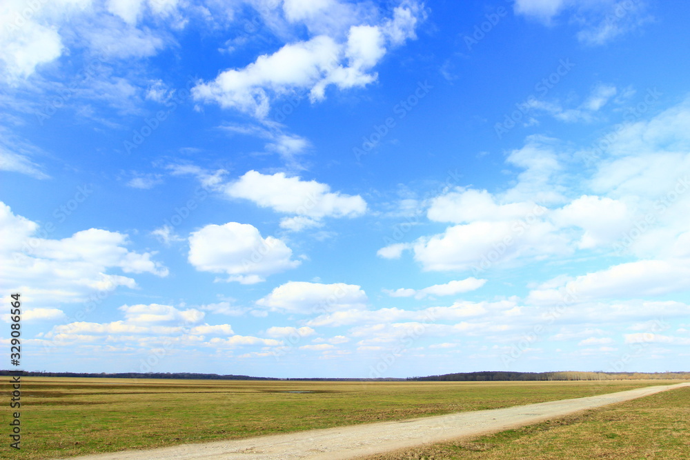 Farm road, green meadow and blue sky in background Farm road, green meadow and blue sky in background