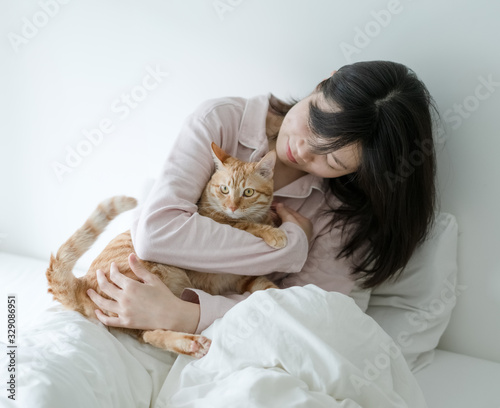 Asian woman hugging a cat on the bed
