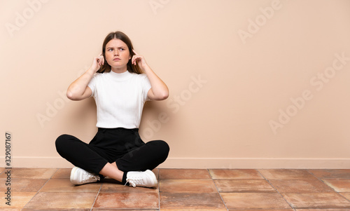 Ukrainian teenager girl sitting on the floor having doubts and thinking