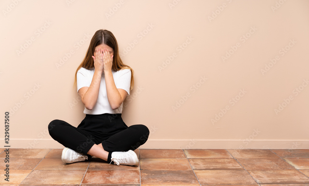 Ukrainian teenager girl sitting on the floor with tired and sick expression Ukrainian teenager girl sitting on the floor with tired and sick expression