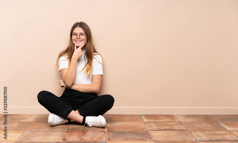 Ukrainian teenager girl sitting on the floor with glasses and smiling Ukrainian teenager girl sitting on the floor with glasses and smiling