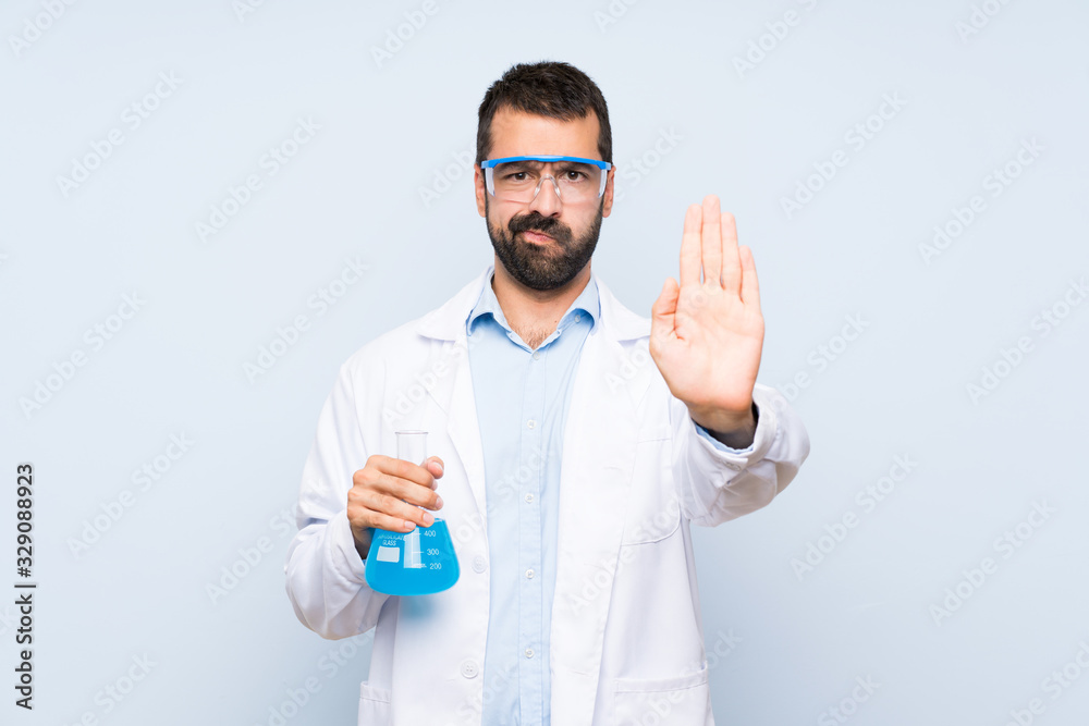 Young scientific holding laboratory flask over isolated background making stop gesture Young scientific holding laboratory flask over isolated background making stop gesture