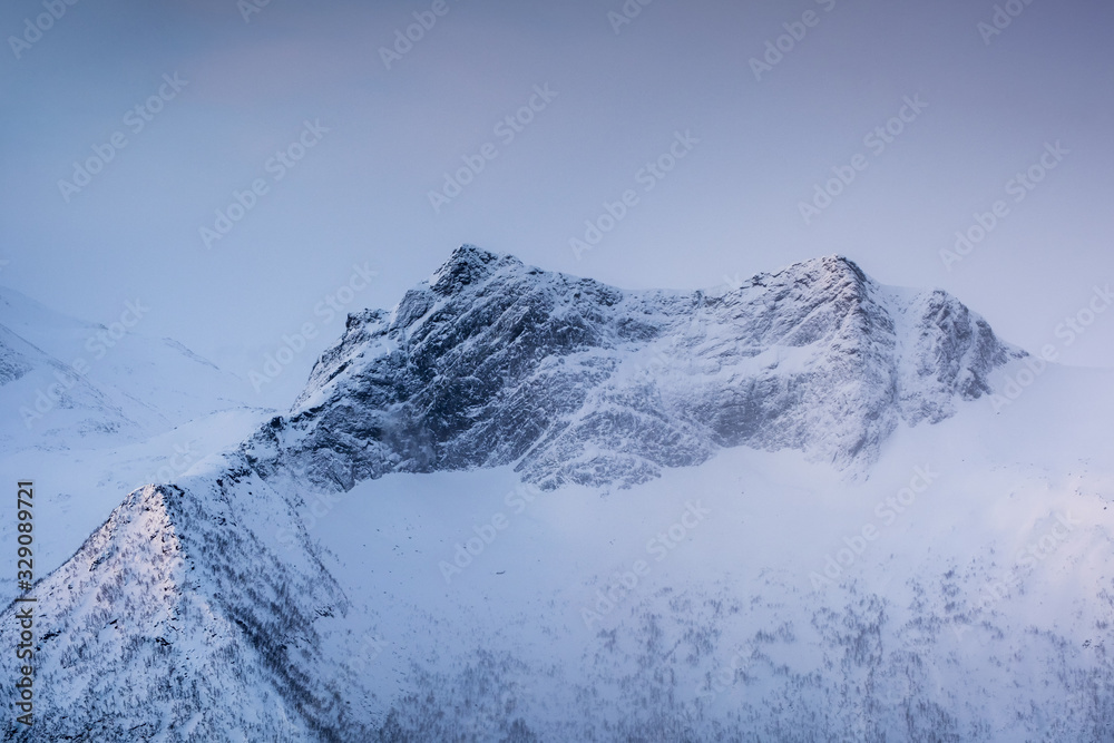 Snowy mountain peak with light in foggy