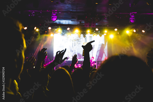 A crowd of people raising their arms up during a concert. They are enjoying the music. Selective focus.