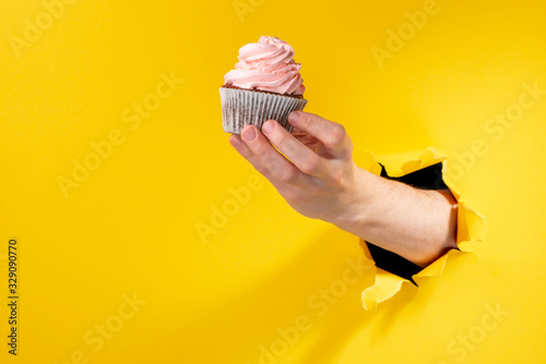 Hand holding a cupcake with pink buttercream swirl photo