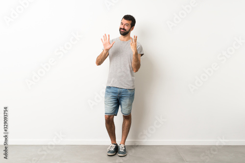 A full-length shot of handsome man with beard counting eight with fingers