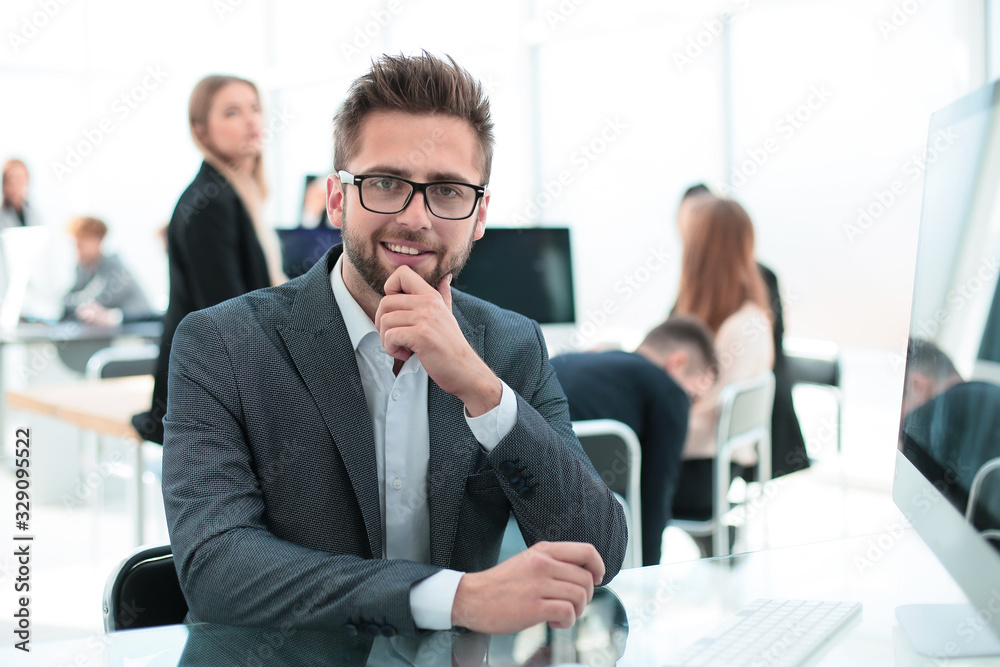 successful young businessman sitting at an office Desk.