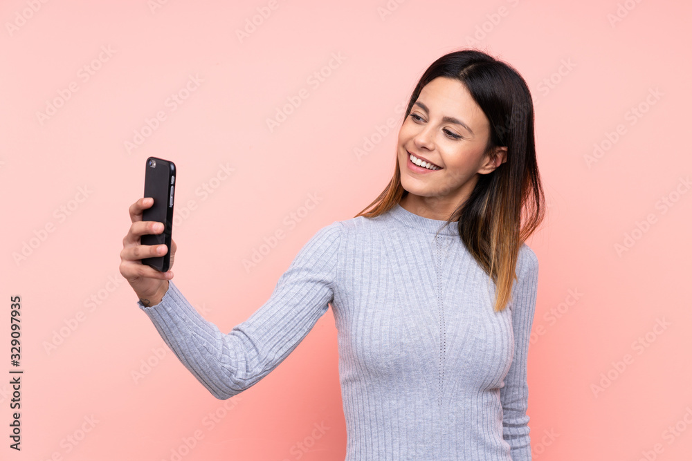 Woman over isolated pink background making a selfie Woman over isolated pink background making a selfie
