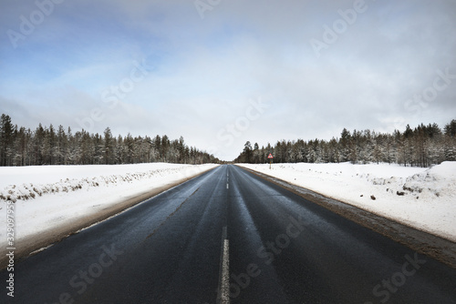 A view of the empty asphalt road through the coniferous forest on a cloudy day. Dramatic blue sky. Karelia north, Lapland, Kuito lake photo