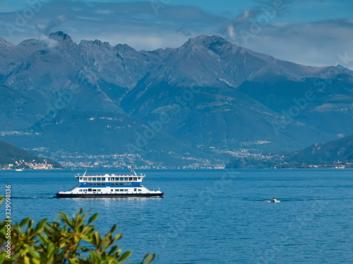 view of Lake Como, mountains, blue sky with white clouds and ferry, Bellagio, Italy