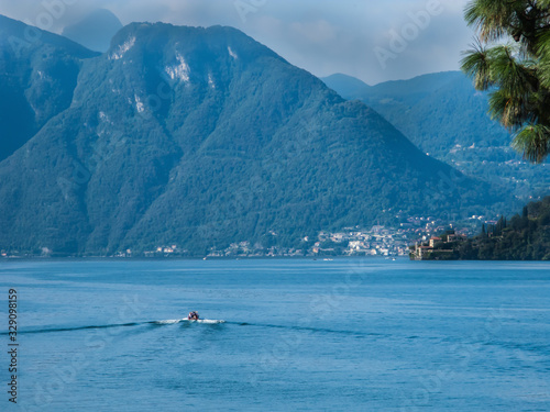 view of Lake Como, mountains, blue sky with white clouds and boat, Bellagio, Italy