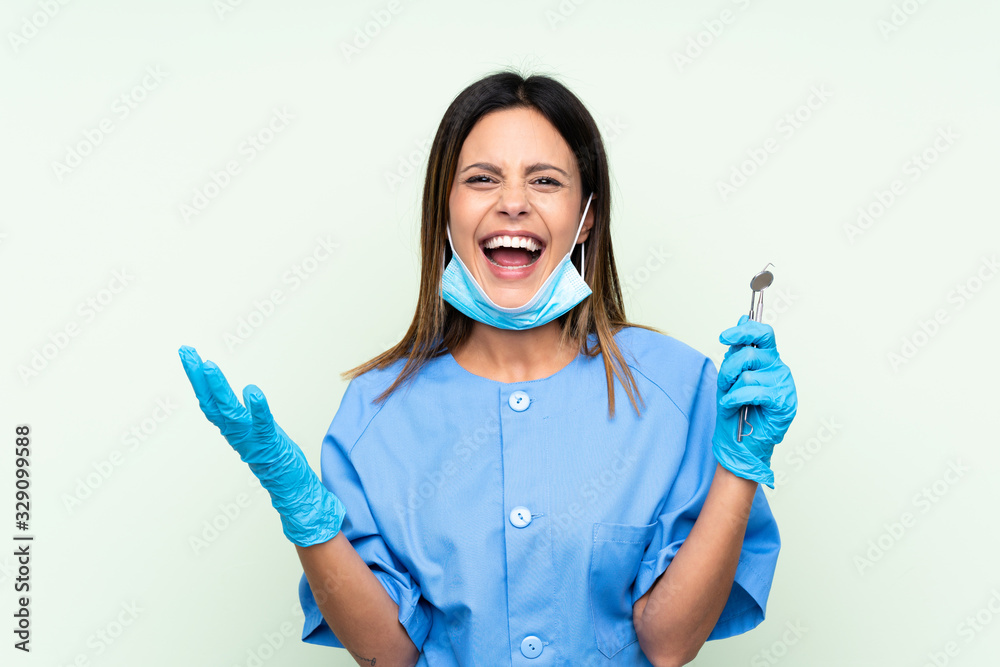 Woman dentist holding tools over isolated green background unhappy and frustrated with something Woman dentist holding tools over isolated green background unhappy and frustrated with something
