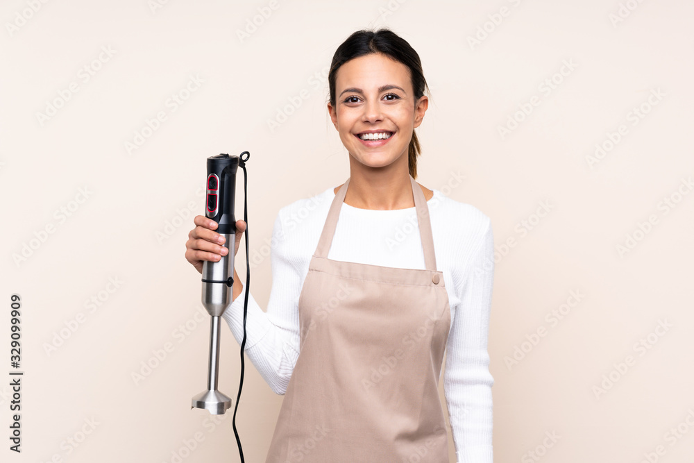 Woman using hand blender over isolated background smiling a lot Woman using hand blender over isolated background smiling a lot