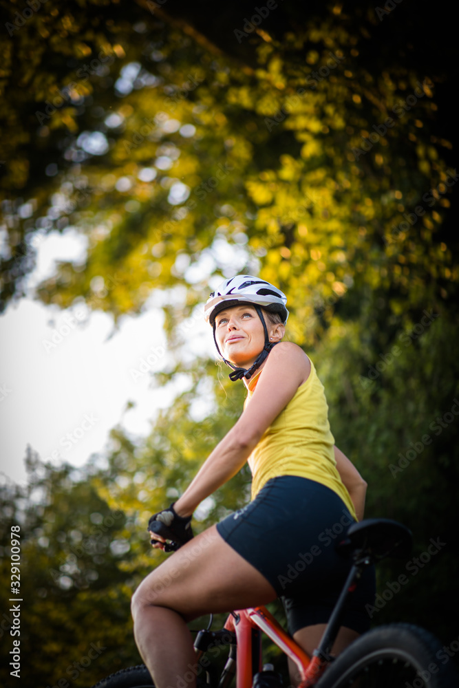 Pretty, young woman biking on a mountain bike enjoying healthy active lifestyle outdoors in summer (shallow DOF) Pretty, young woman biking on a mountain bike enjoying healthy active lifestyle outdoors in summer (shallow DOF)