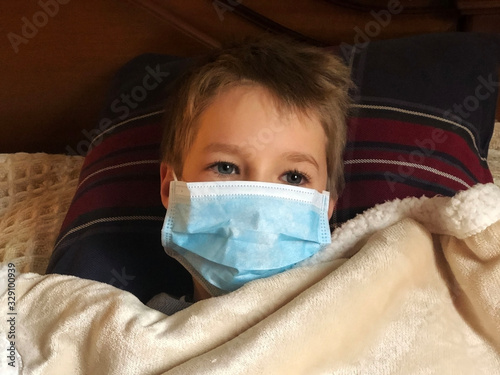 little boy in bed wearing medical mask under blanket. Sick boy. Patient. treatment