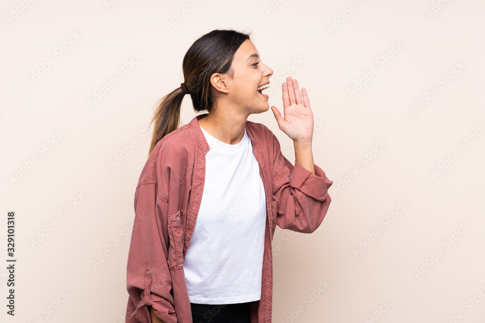 Woman over isolated background shouting with mouth wide open to the lateral Woman over isolated background shouting with mouth wide open to the lateral