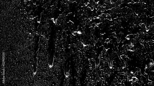 Rain water droplets trickling heavily down the window pane at night