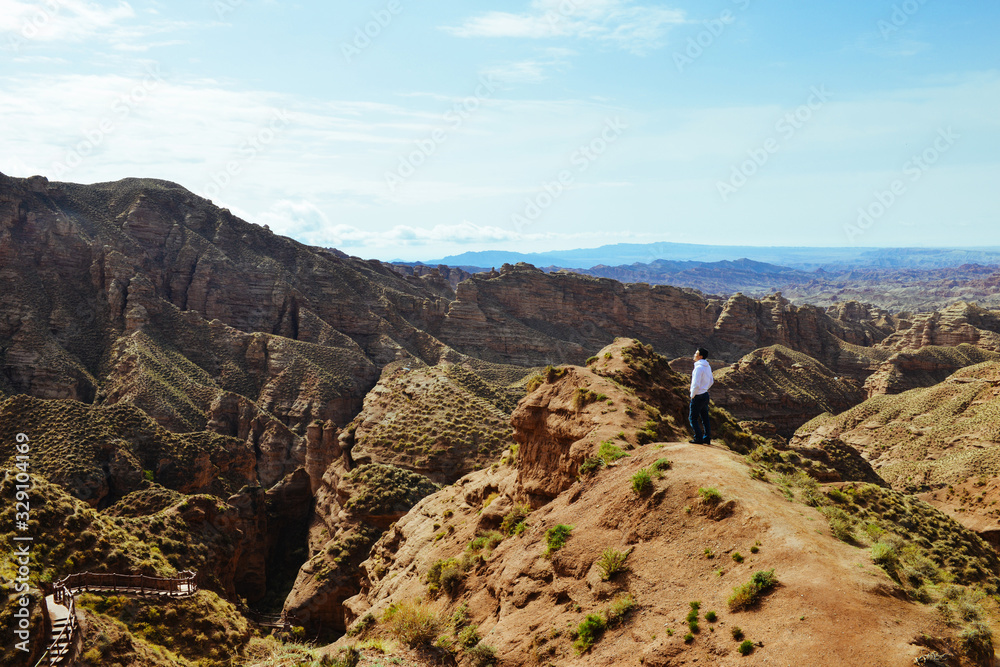 Young man enjoys the view of valley on top of hill