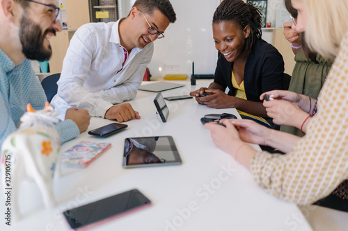 Smiling multiethnic small tech startup team having fun testing new console game