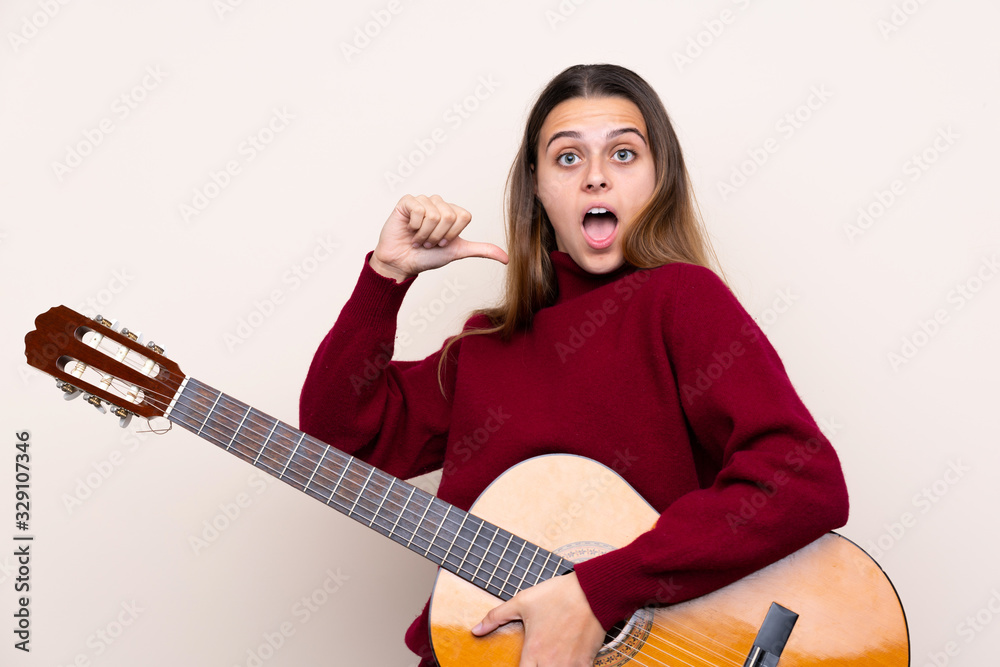 Teenager girl with guitar over isolated background with surprise facial expression Teenager girl with guitar over isolated background with surprise facial expression