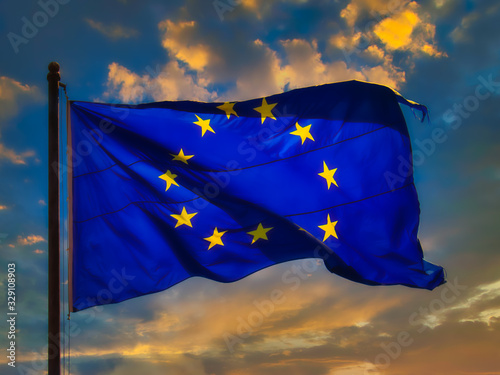 The European Union (EU) flag flies in the wind at sunset. The official symbol of the EU.
