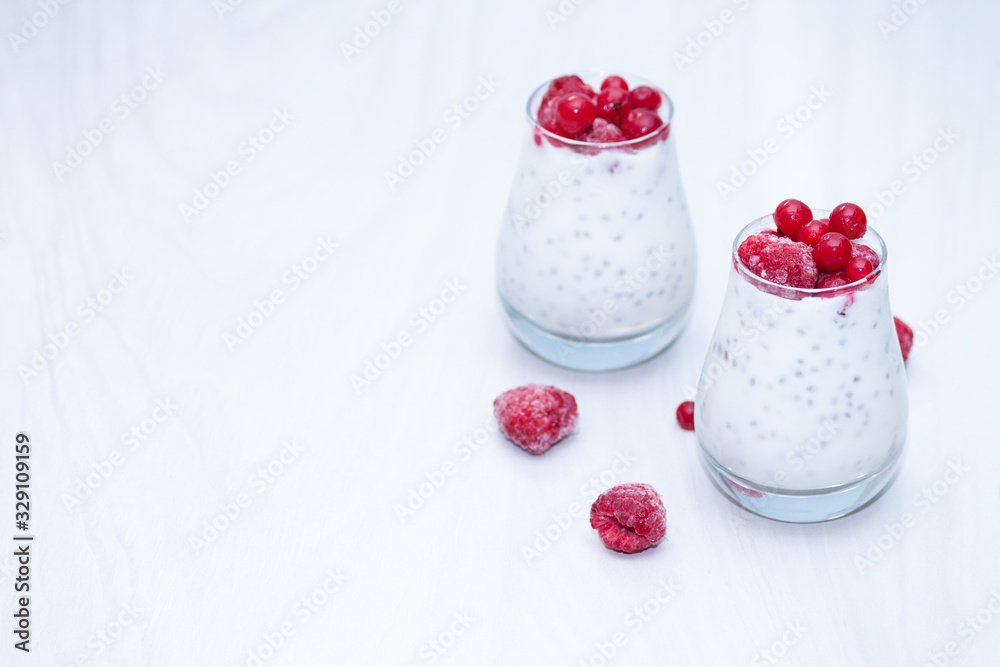 Healthy vanilla chia pudding with red berries on white wooden background. Healthy snack concept. Copy space. Healthy vanilla chia pudding with red berries on white wooden background. Healthy snack concept. Copy space.