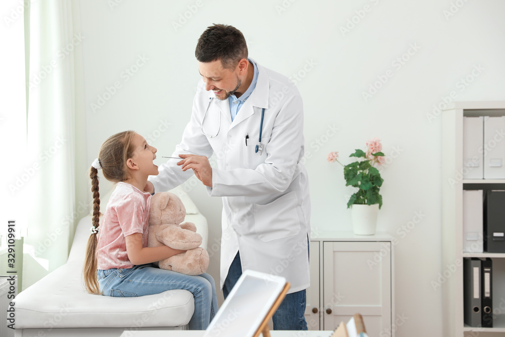 Children's doctor examining little patient's throat in clinic Children's doctor examining little patient's throat in clinic