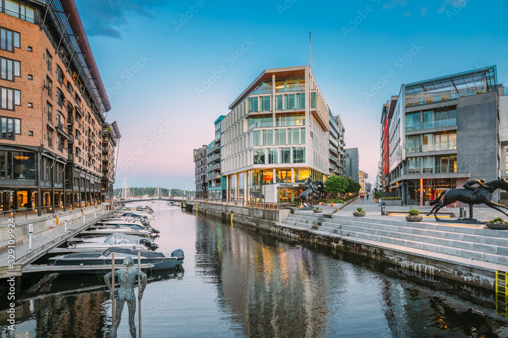 Oslo, Norway. View Of Residential Multi-storey Houses In Aker Brygge District In Summer Evening. Famous And Popular Place. Pier Jetty With Boats.