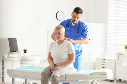 Male orthopedist examining patient with injured neck in clinic photo