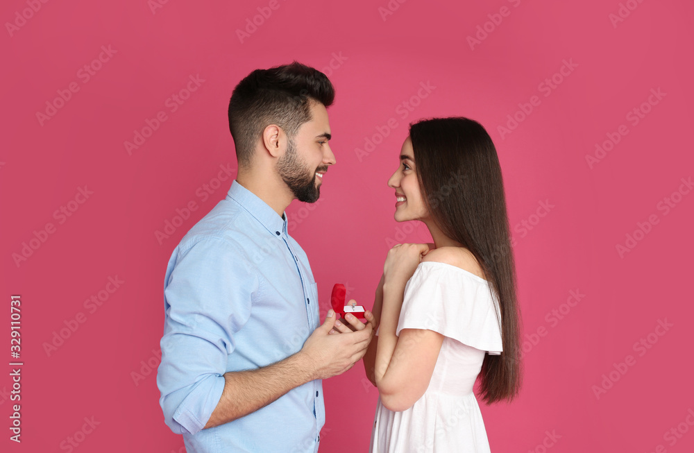 Man with engagement ring making marriage proposal to girlfriend on crimson background Man with engagement ring making marriage proposal to girlfriend on crimson background