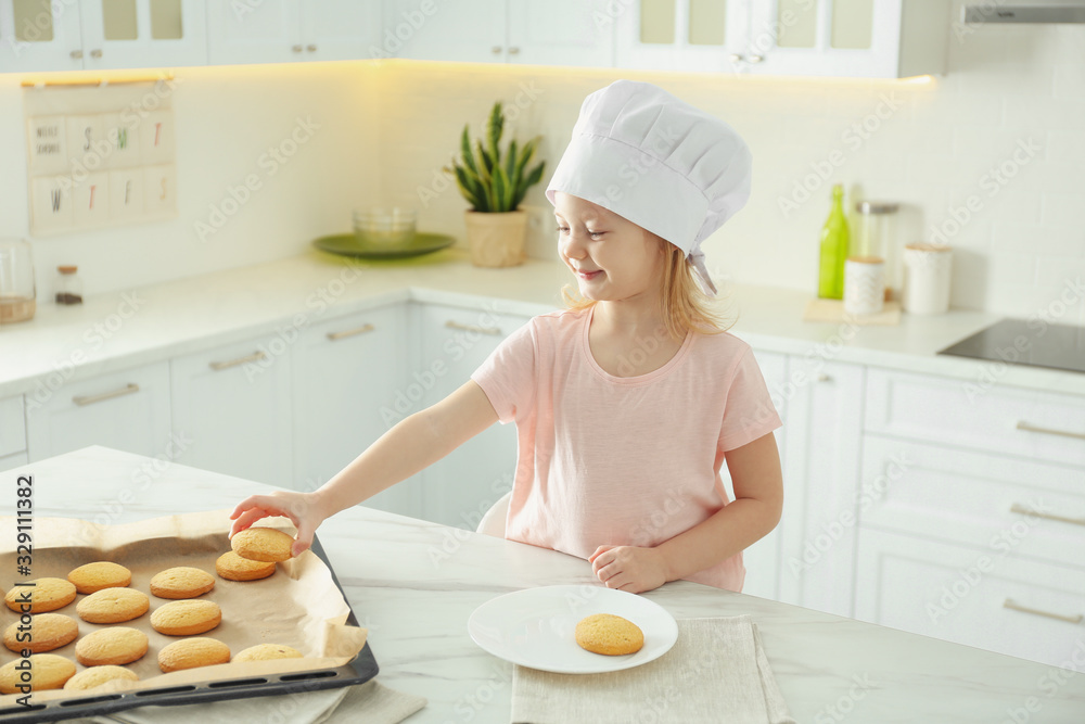 Little girl wearing chef hat baking cookies in kitchen Little girl wearing chef hat baking cookies in kitchen