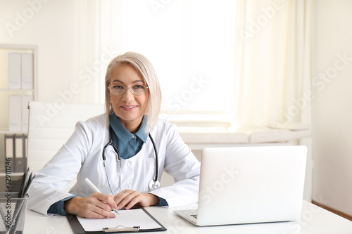 Portrait of mature female doctor in white coat at workplace © New Africa