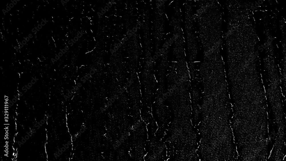 Rain water droplets trickling down the window pane at night