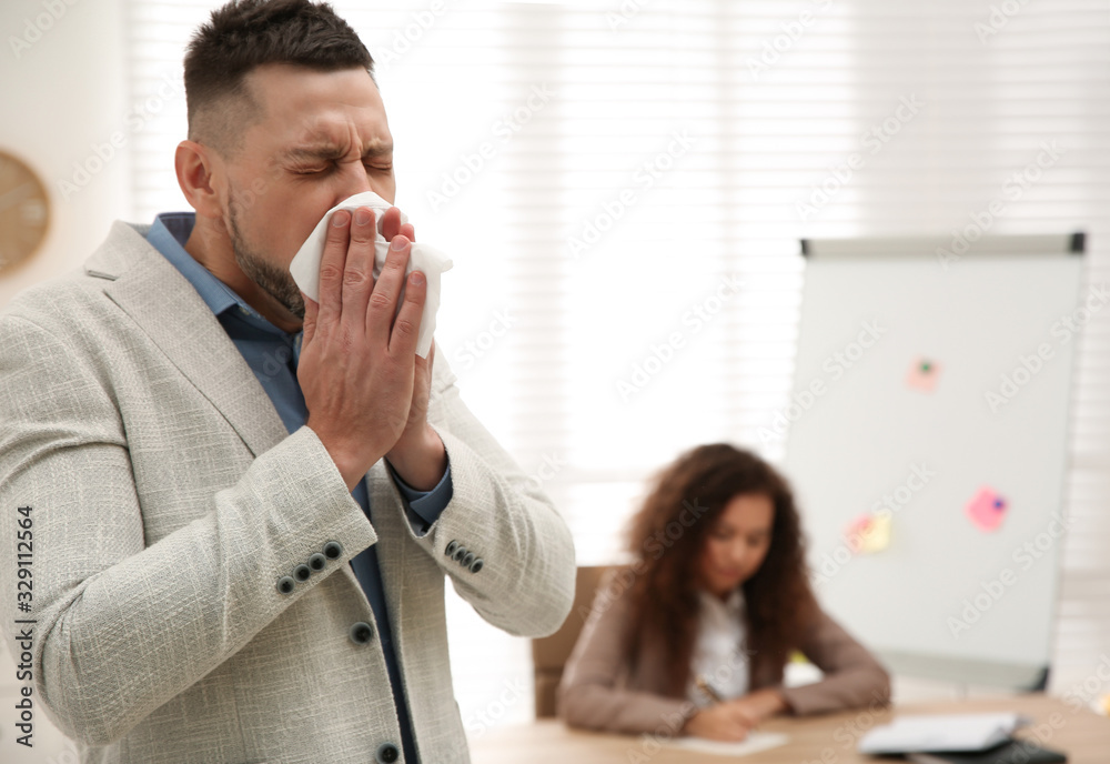 Sick man sneezing in office. Influenza virus Sick man sneezing in office. Influenza virus