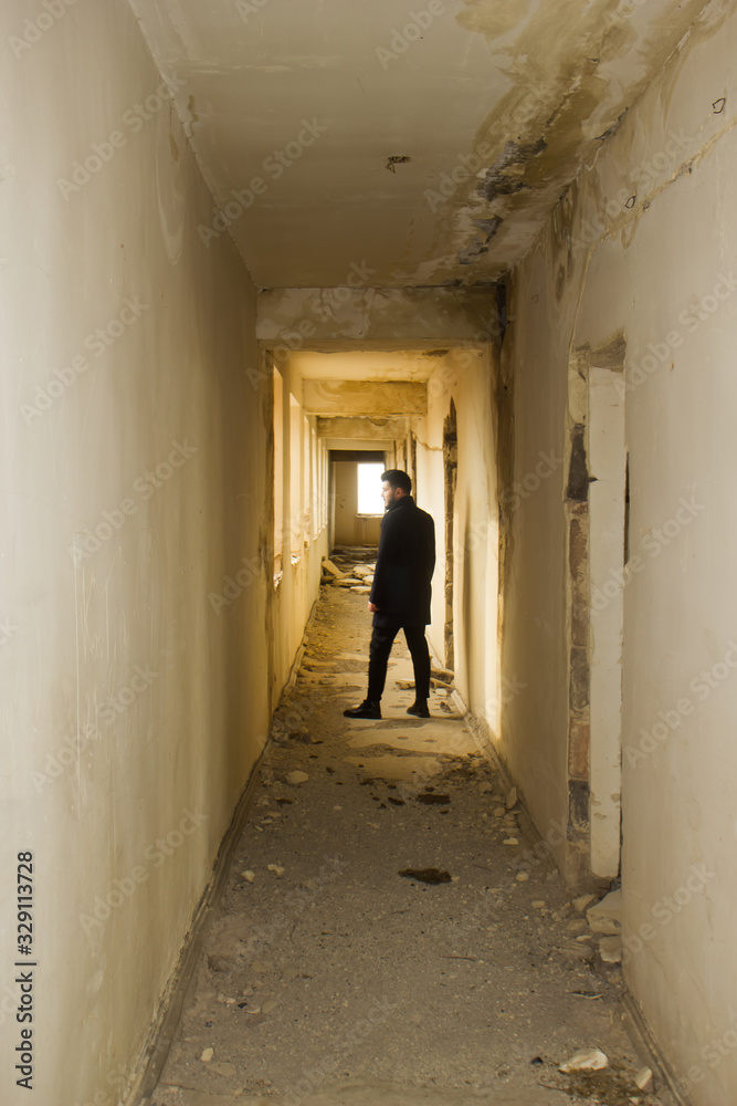 a lonely gay man standing  in the corridor of abandoned house