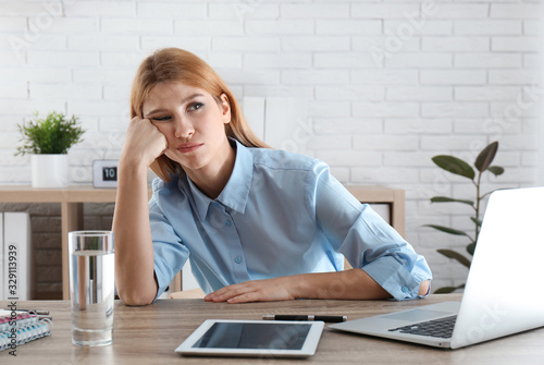 Lazy employee wasting time at table in office photo