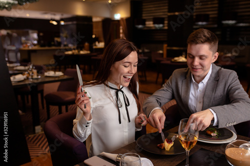 happy young caucasian couple sit in restaurant  man and woman enjoy evening in rich luxury restaurant  they eat delicious tasty food