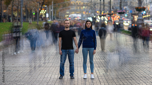 The man and woman stand on the crowded street and hold hands