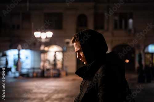 Depressed , lonely teenager walking the streets by night alone and thinking with head bowed 