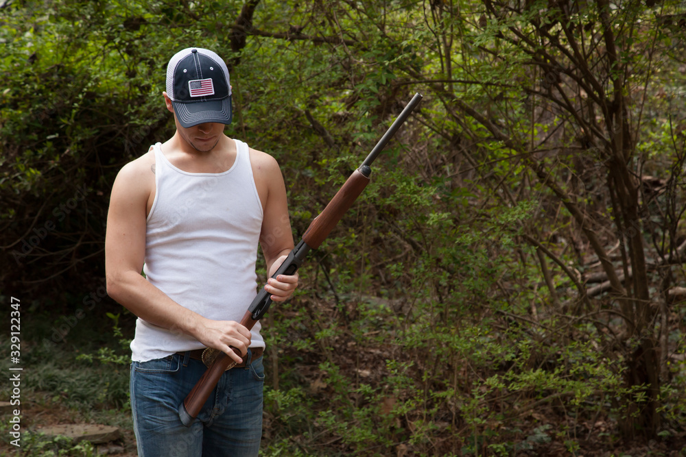 Fototapeta premium Thoughtful man with a shotgun in the woods