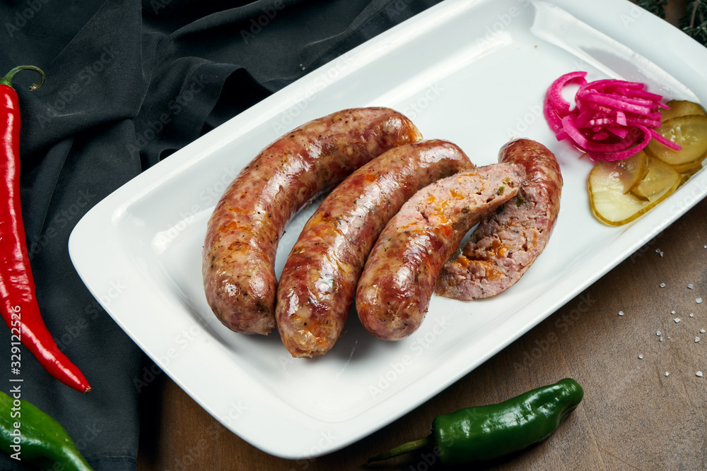 Appetizing juicy pork minced sausage grilled in a smoker with cheddar in a white plate with canned vegetables. German beer snack Appetizing juicy pork minced sausage grilled in a smoker with cheddar in a white plate with canned vegetables. German beer snack