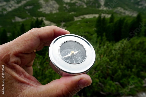 compass in the hands of a tourist, mountain landscape in the background, High Tatras mountain 