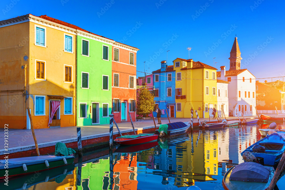 Obraz premium Street with colorful buildings in Burano island, Venice, Italy. Architecture and landmarks of Burano, Venice postcard. Scenic canal and colorful architecture in Burano island near Venice, Italy